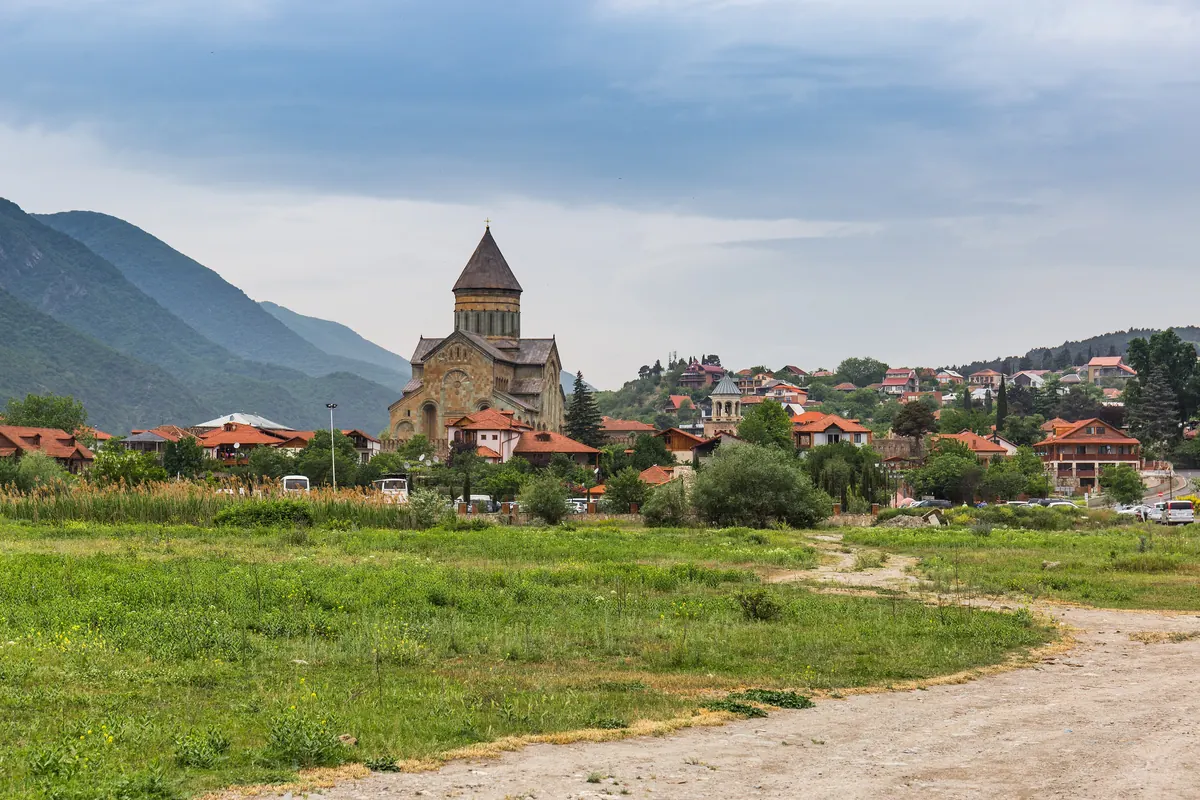 Svetitskhoveli Cathedral rising above the houses of Mtskheta with green mountains behind
