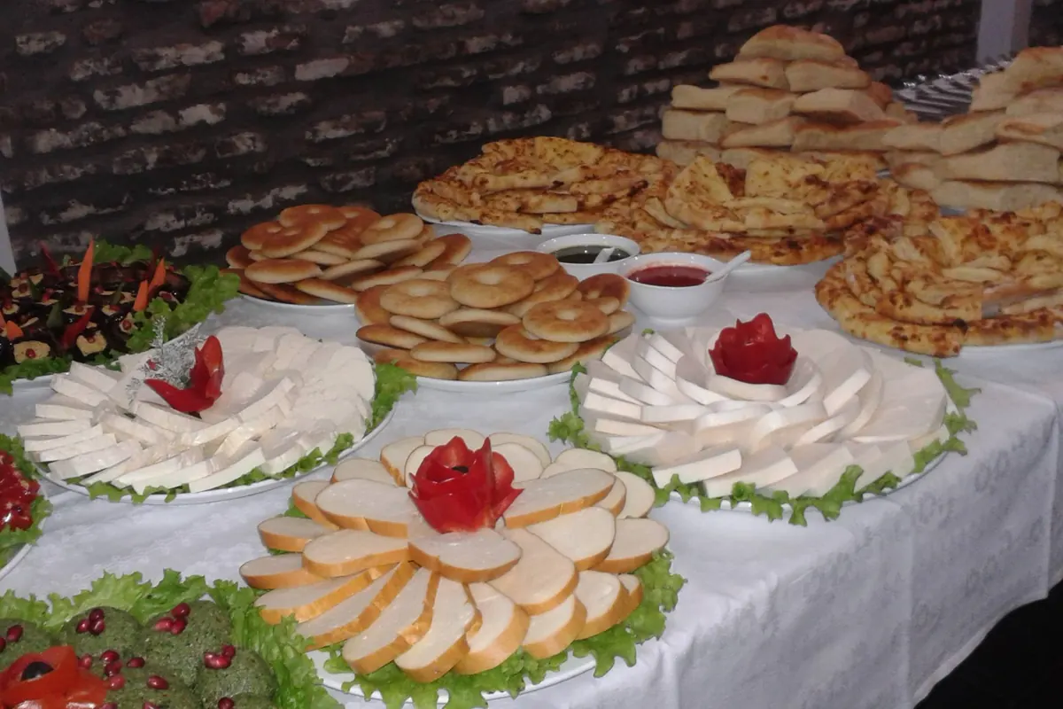 A buffet of Georgian breads, cheeses, vegetable dishes and sliced tomatoes arranged on a white tablecloth
